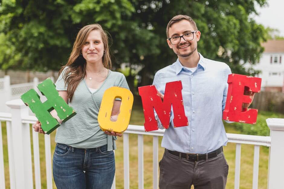 Two people holding the leters h o m e, home