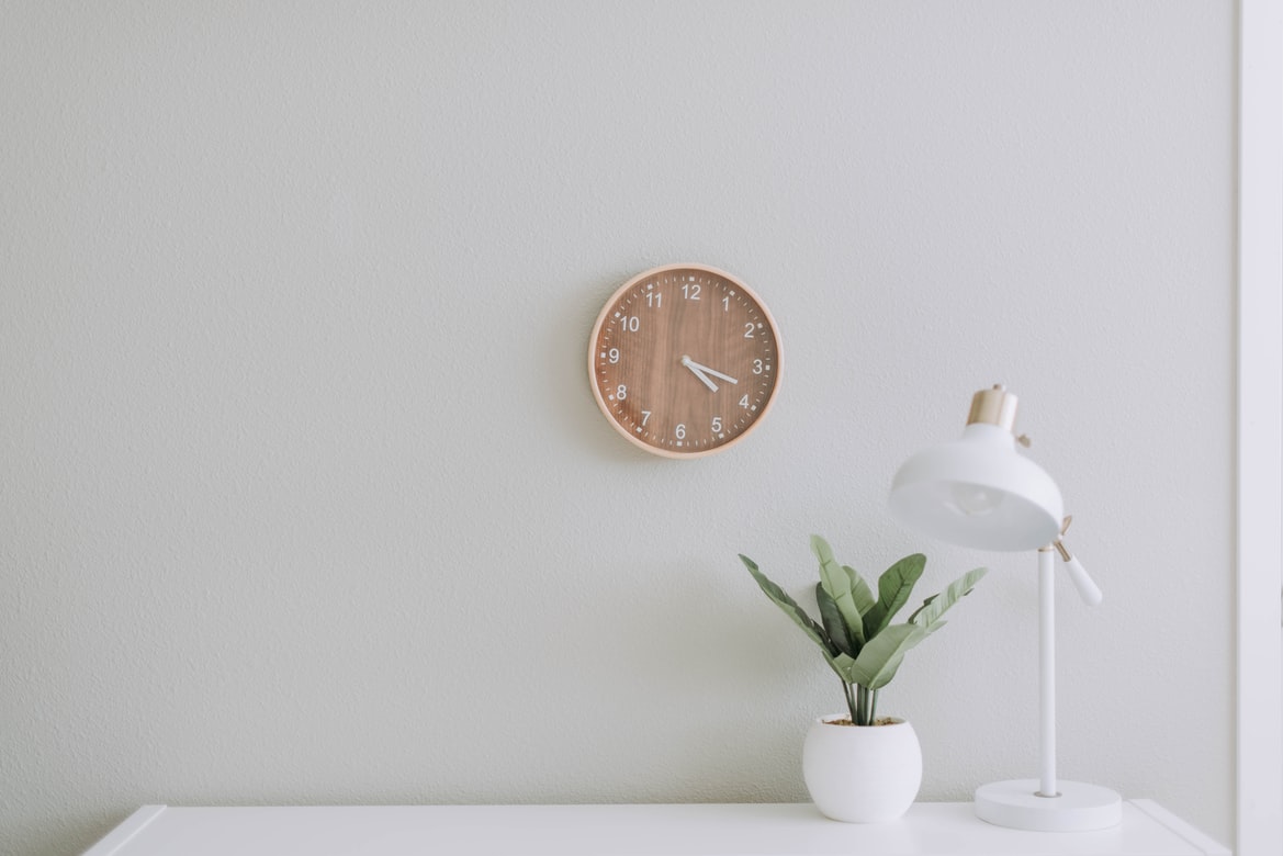 table with a plant and a lamp. clock on wall