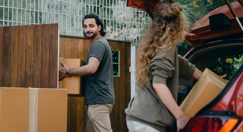 A couple of people moving boxes from a car