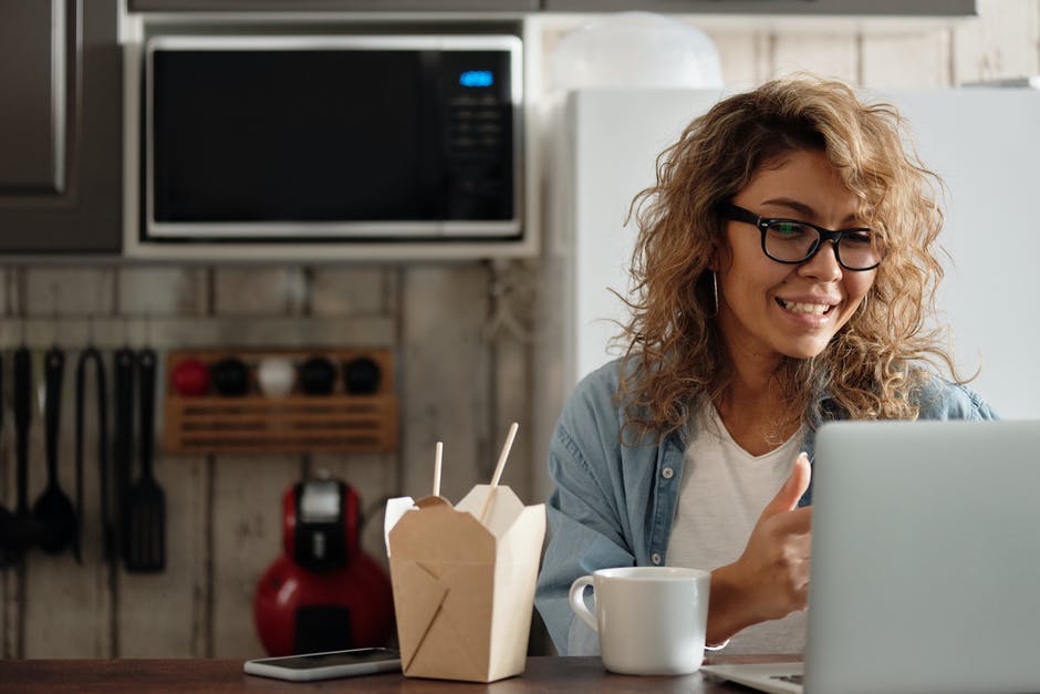 Person sitting in the kitchen with a laptop and take-out food