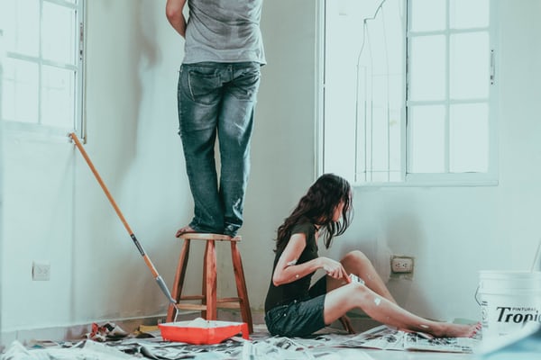 Two people painting a room white