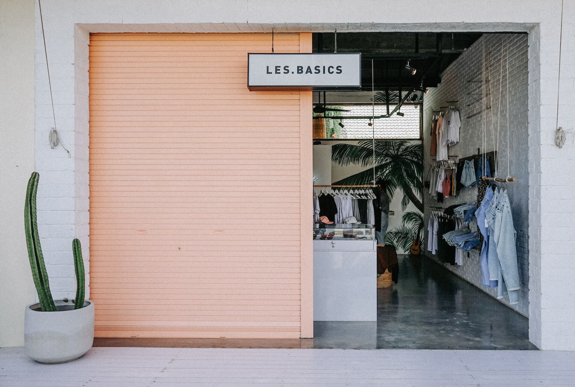 outside of a store, door halfway open, clothing displayed in store
