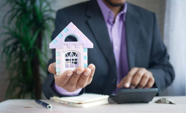 Man in a suit holding a house in his hand