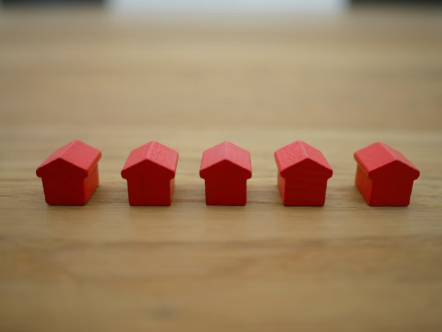 5 red wooden houses in a row on a table