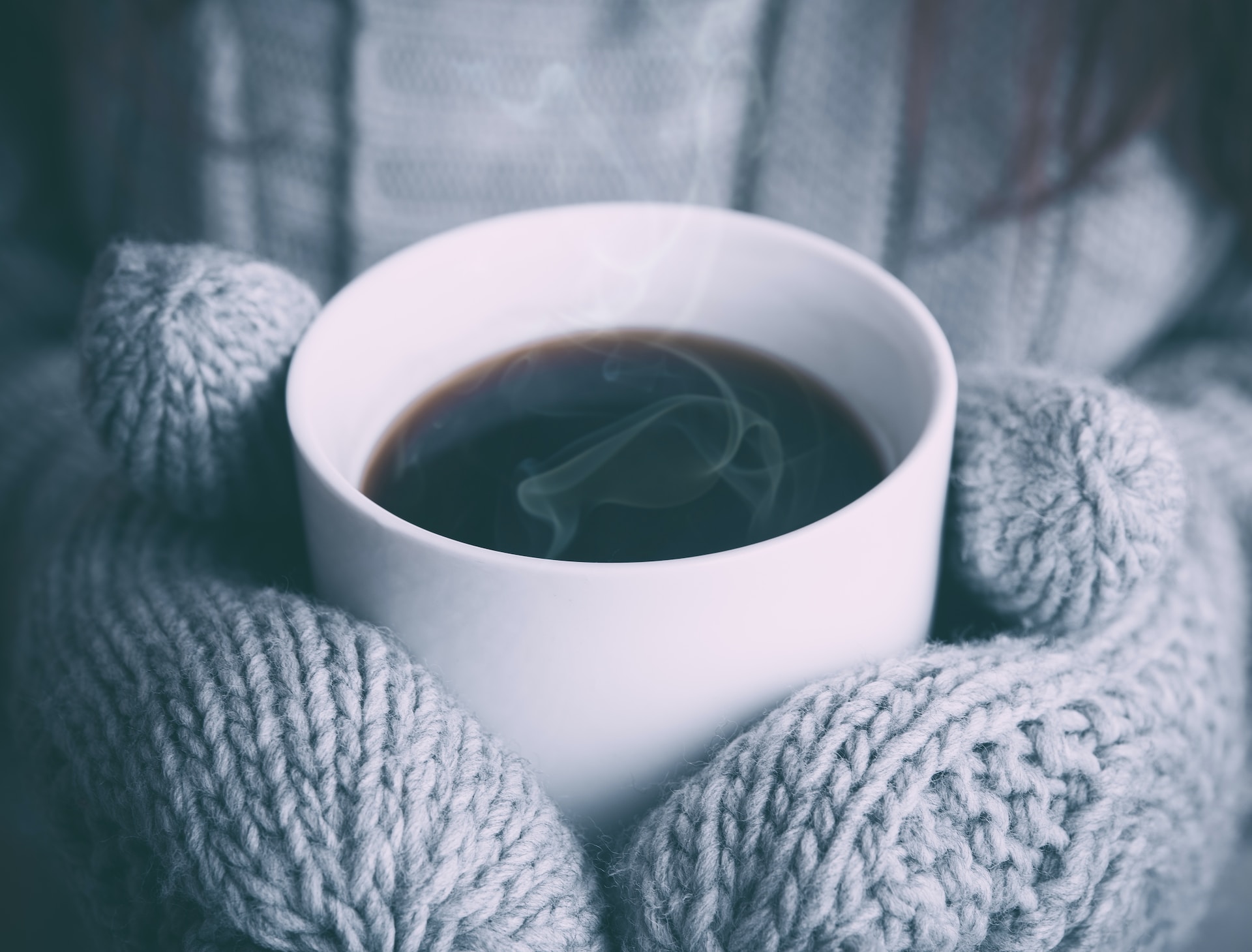 person with gloves holding a cup of coffee